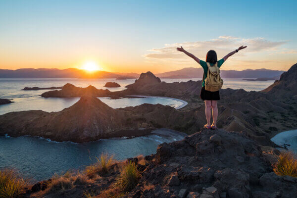 A woman standing on the peak of Padar Island in sunset time.