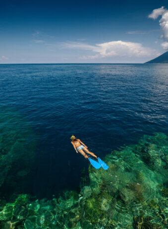 Lady snorkeling over reef wall